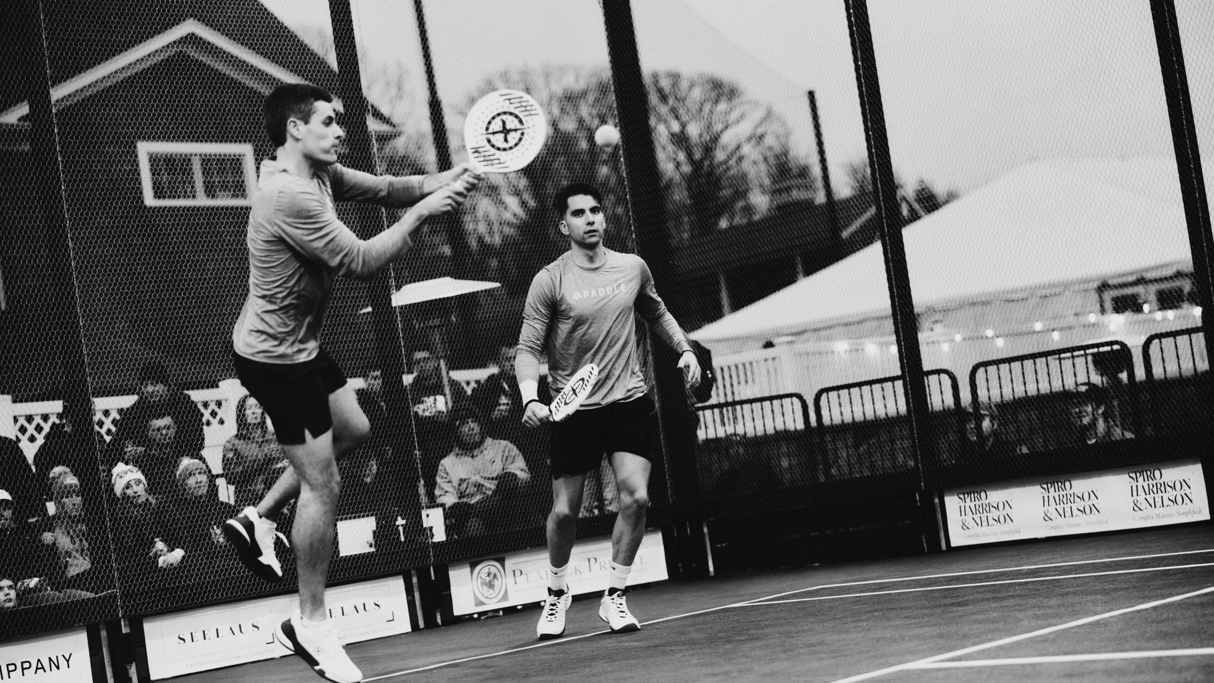 M4 paddle players on court — black and white